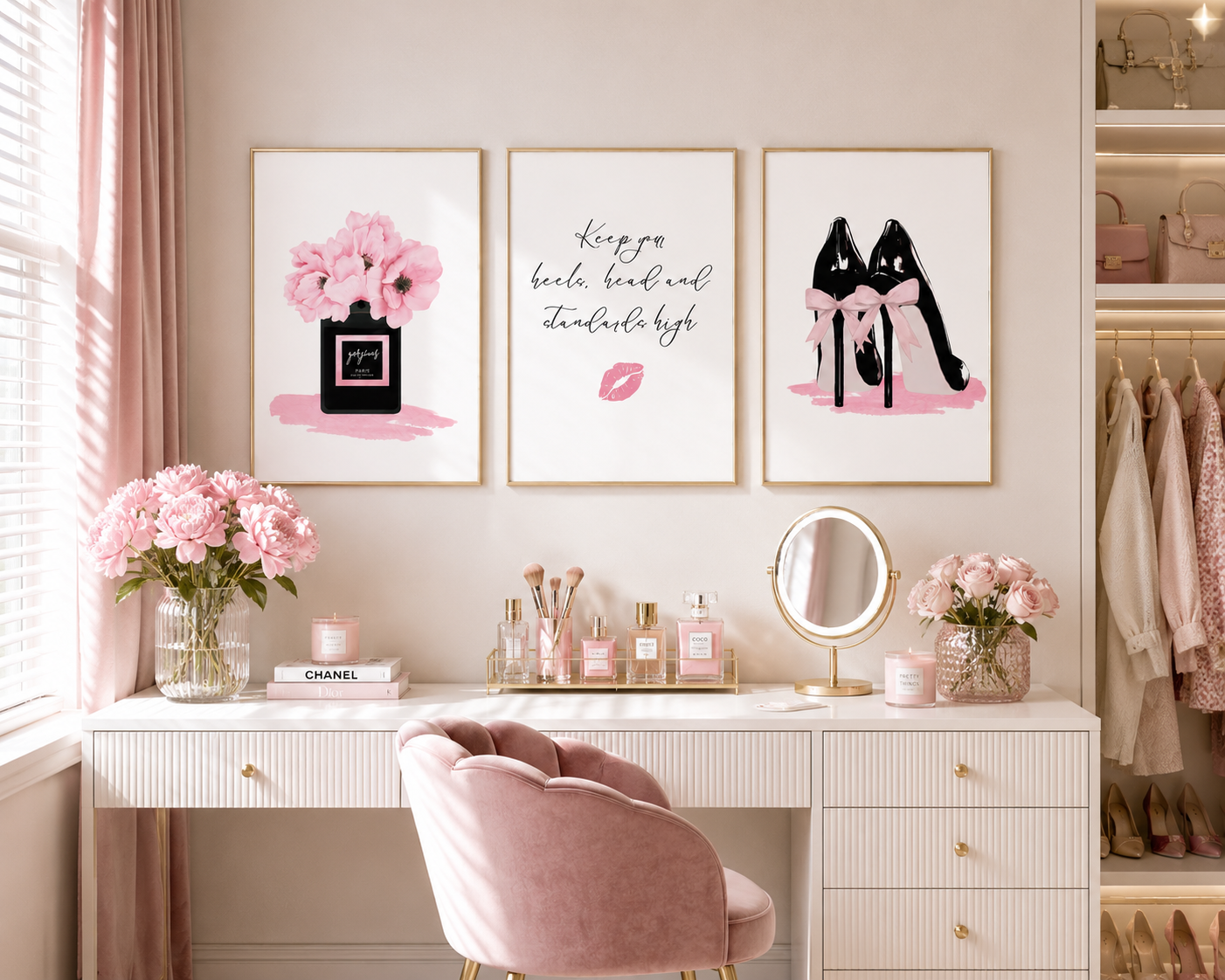 A styled vanity area with three framed wall art prints above a white desk and blush pink chair. The prints show pink flowers in a perfume bottle, cursive text with a pink lip, and black high heels with pink bows.
