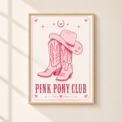 A framed art print featuring a pink cowboy hat and boots design with the text 'PINK PONY CLUB' on a cream background, hanging on a light beige wall with soft window shadow patterns.