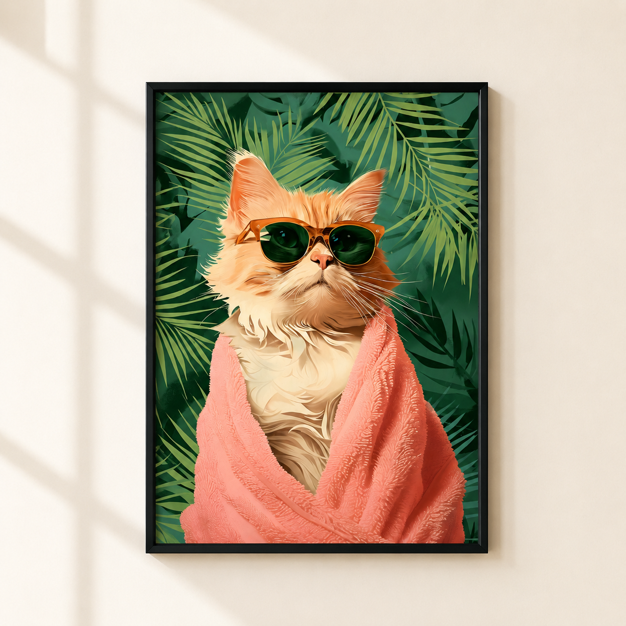 A framed art print featuring an orange tabby cat wrapped in a pink towel and wearing dark sunglasses, set against a background of green tropical leaves. The framed print is mounted on a light beige wall with soft window shadow patterns.