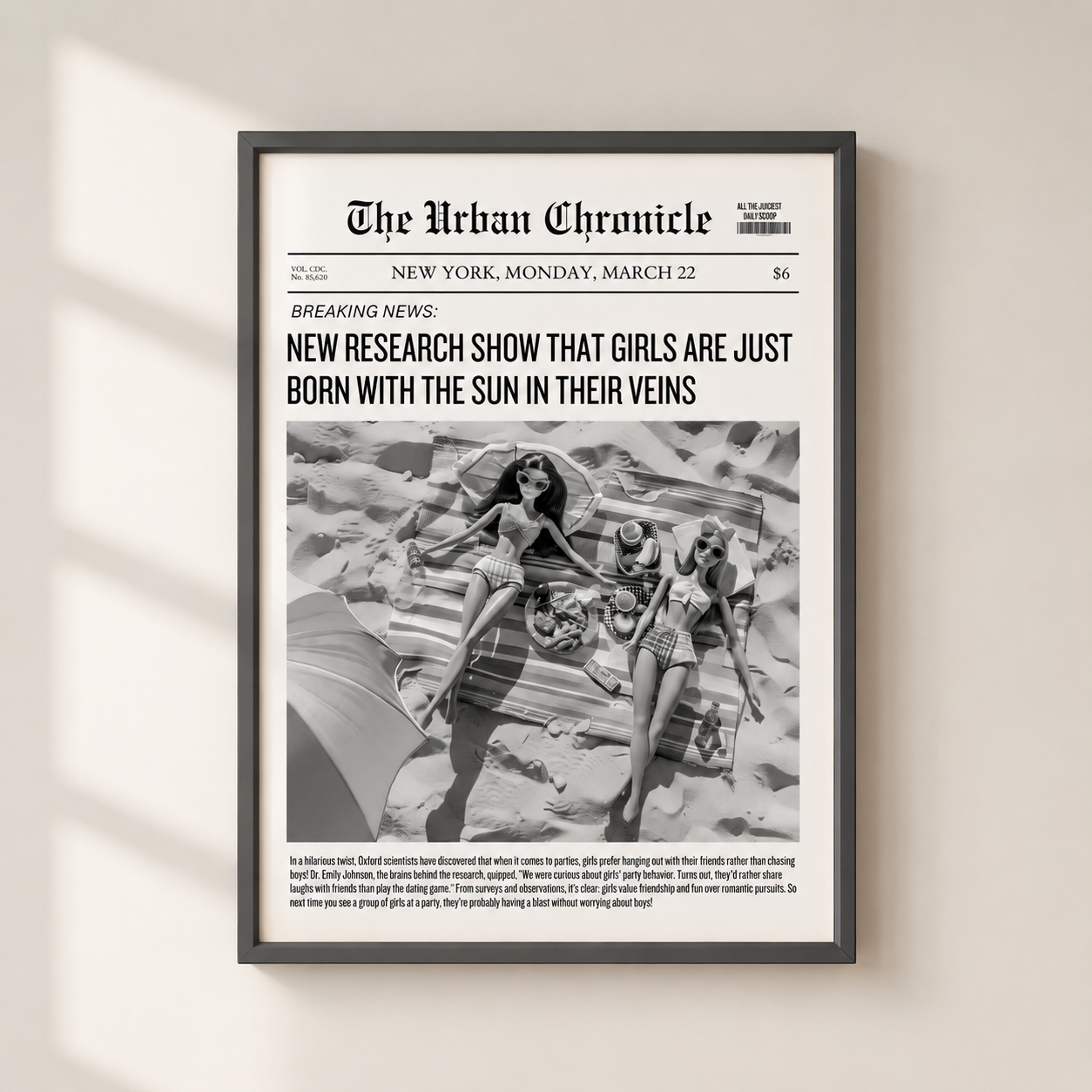A framed black-and-white newspaper-style art print titled "The Urban Chronicle" hangs on a light beige wall. The print features a bold headline and a central photograph of three women on a beach, with smaller text below.