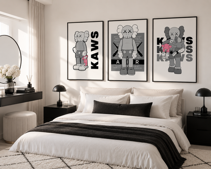 Three framed KAWS art prints in black, white, and gray hang above a neatly made bed in a modern, neutral-toned bedroom.