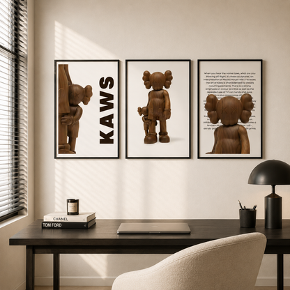 Three framed wall art prints featuring stylized brown character illustrations and text, displayed above a dark desk in a modern room with a chair, lamp, and window blinds.