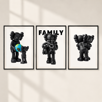Three framed wall art prints showing stylized black cartoon figures in family-themed scenes, mounted on a light beige wall with soft window-shadow lighting.