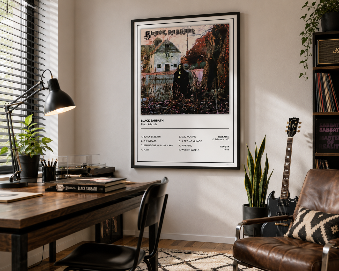 A framed Black Sabbath poster hangs on a beige wall in a styled home office setting with a wooden desk, lamp, chair, guitar, and bookshelves.