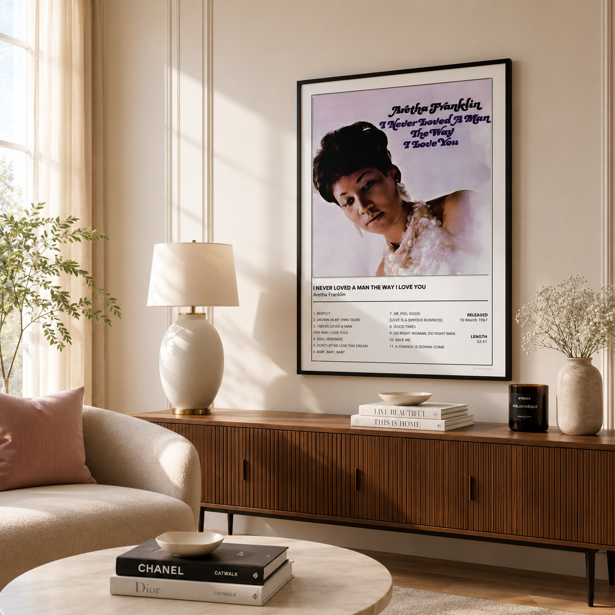 A framed poster of Aretha Franklin,  hanging on a beige wall in a styled living room above a mid-century modern wooden console table.