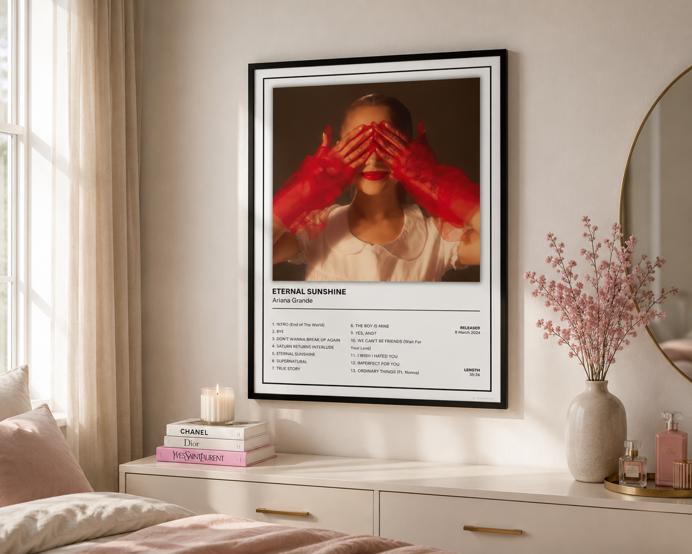 A framed art print featuring a woman with red hands covering her eyes, displayed on a bedroom wall above a white dresser with decorative items.