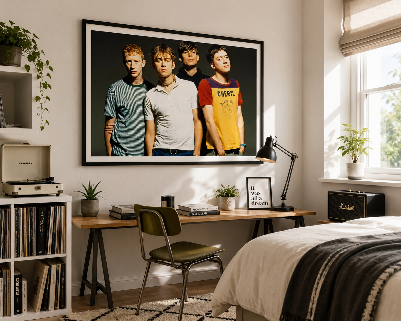 A large framed wall art print of the band Cherish hanging on a bedroom wall above a wooden desk, with a bed, chair, plants, and window visible in the room.
