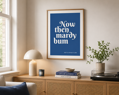 Minimalist blue Arctic Monkeys lyric print in a natural wood frame styled in a contemporary neutral living room with soft furnishings and natural light.