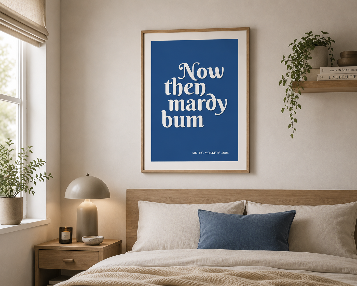 Modern Arctic Monkeys "Now Then Mardy Bum" blue typography poster framed in oak and displayed in a Scandinavian-inspired bedroom interior.