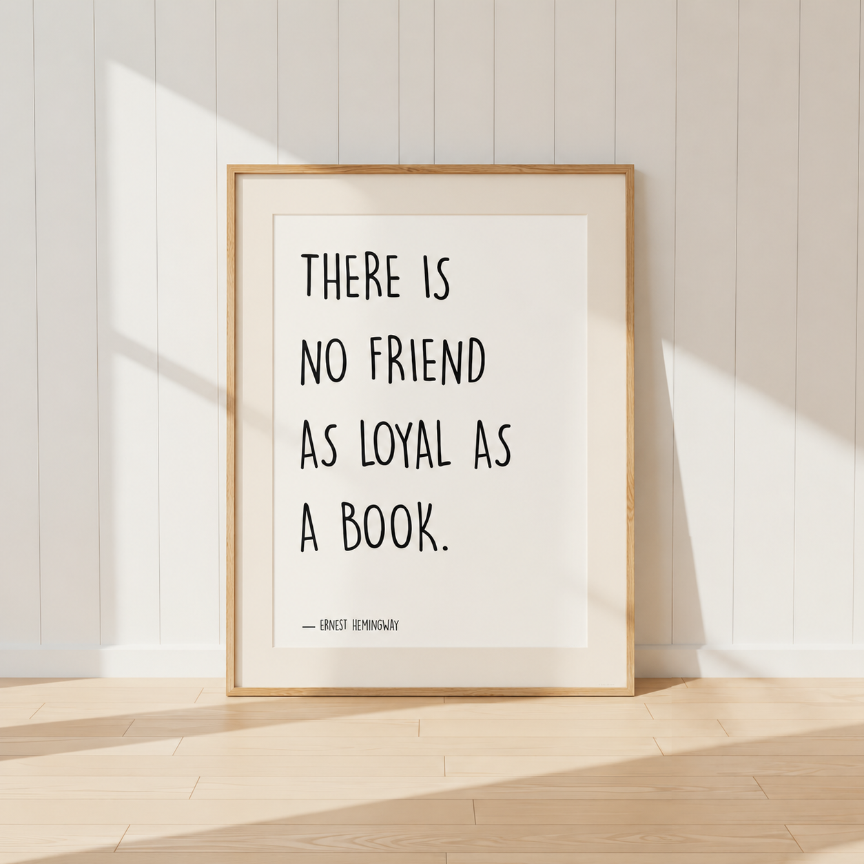 Minimalist Ernest Hemingway quote print featuring the words "There Is No Friend As Loyal As A Book" in black typography, finished with a soft natural mount and light oak frame, perfect for home libraries and reading rooms.