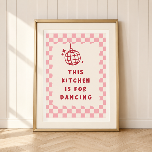 Pink retro kitchen wall art featuring a disco ball illustration and checkerboard border with the quote "This Kitchen Is For Dancing" in a champagne gold frame.