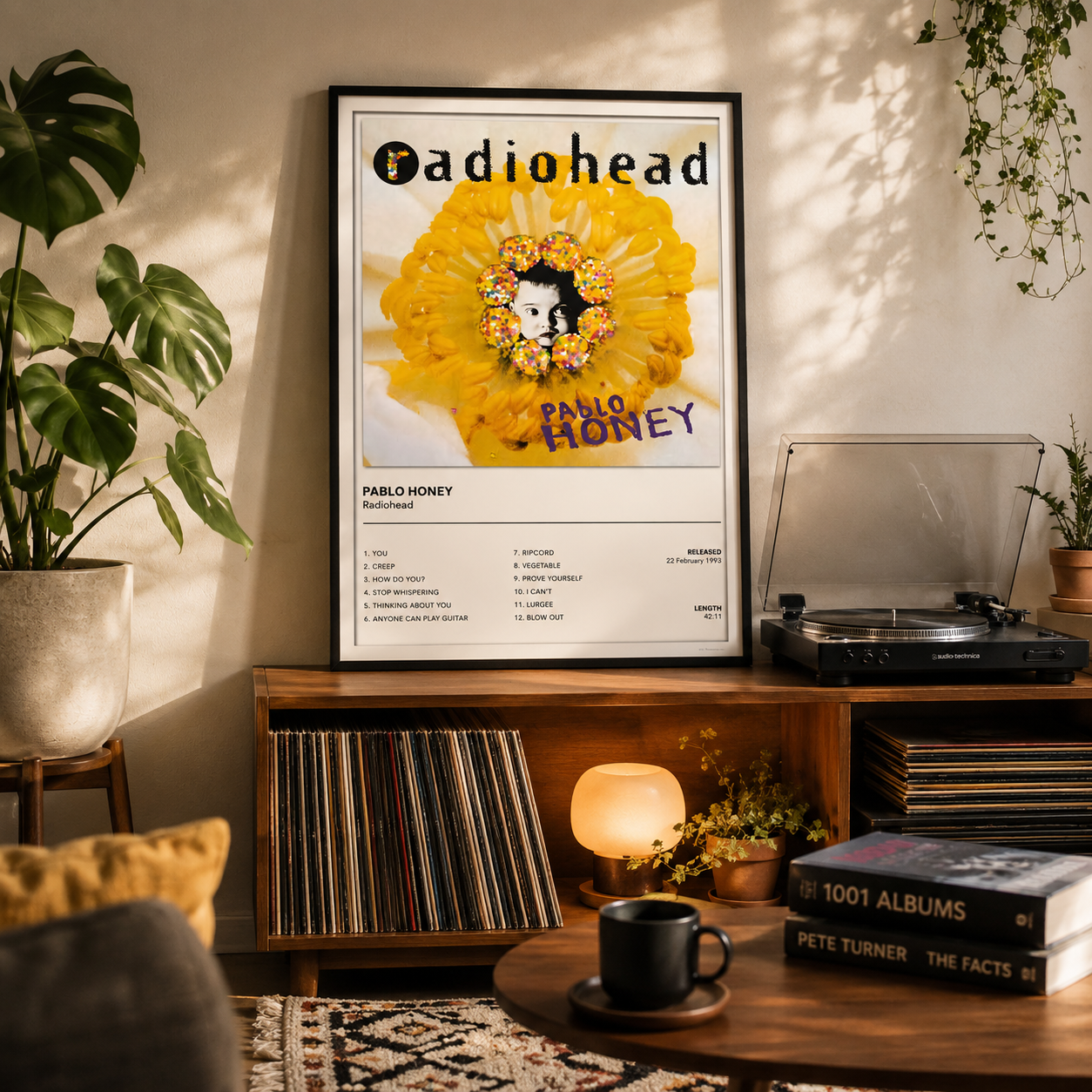 Framed Radiohead Pablo Honey album cover print displayed above a modern record cabinet in a stylish living room.