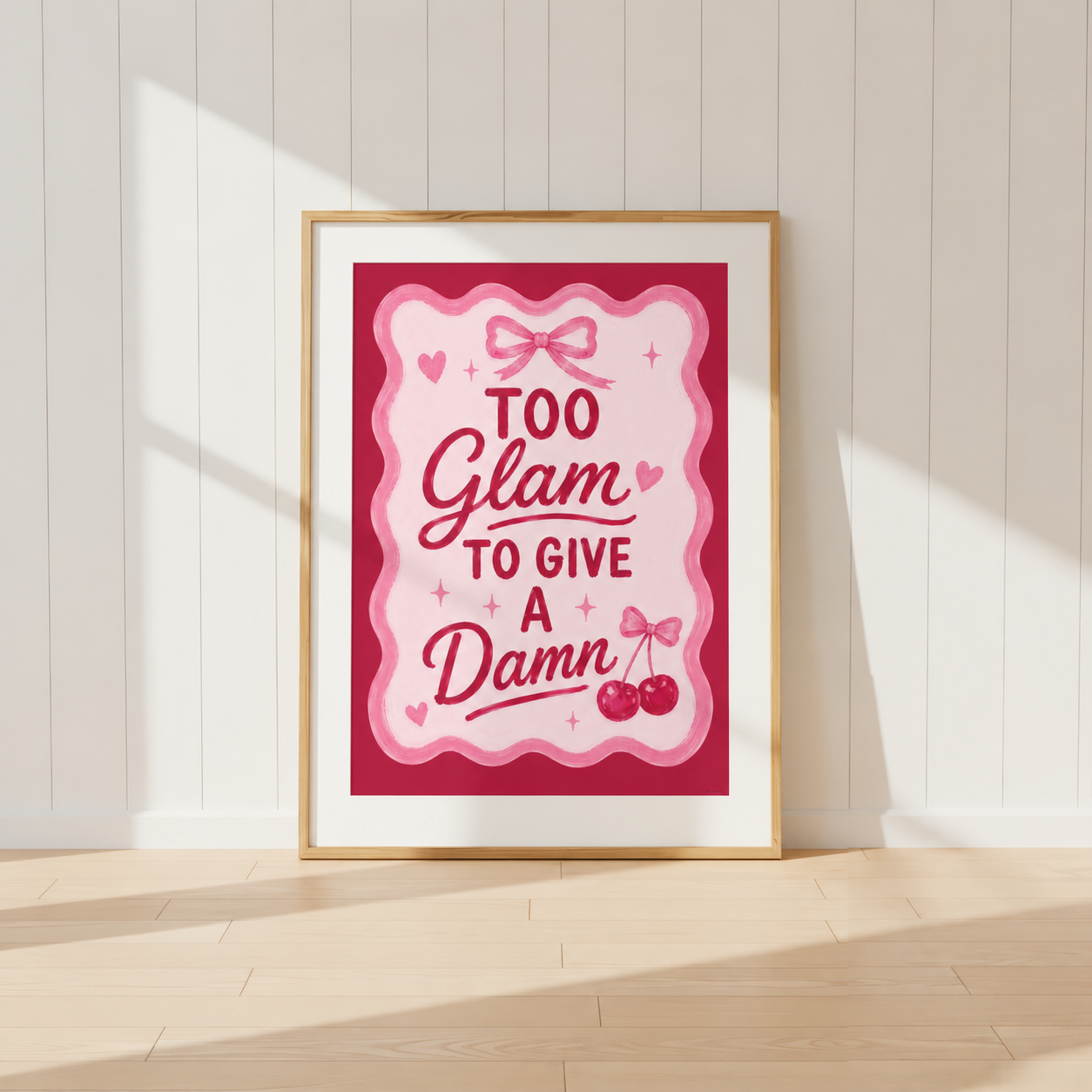 Too Glam To Give A Damn pink coquette wall art print featuring bow and cherry illustrations in a light oak frame.
