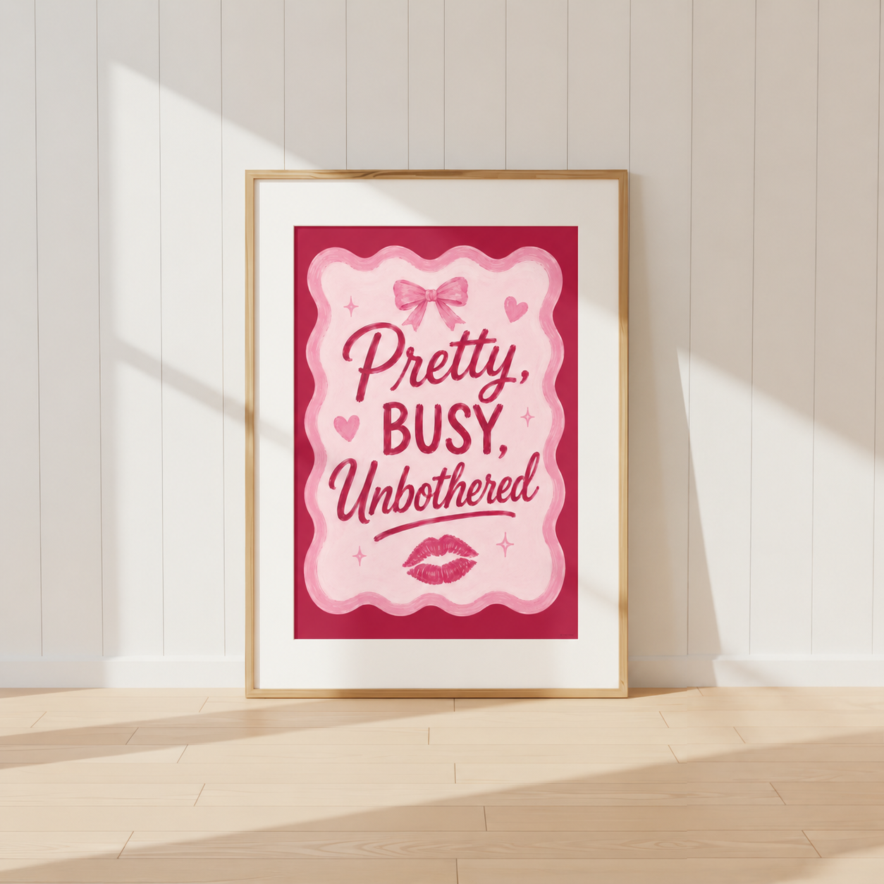 Pretty Busy Unbothered pink coquette wall art print featuring bow and lipstick kiss illustrations in a light oak frame.