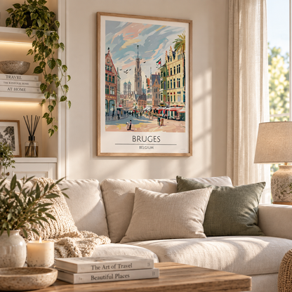 A framed travel poster of Bruges, Belgium, hanging on a beige wall in a beautifully styled living room with a sofa, pillows, and a wooden coffee table.