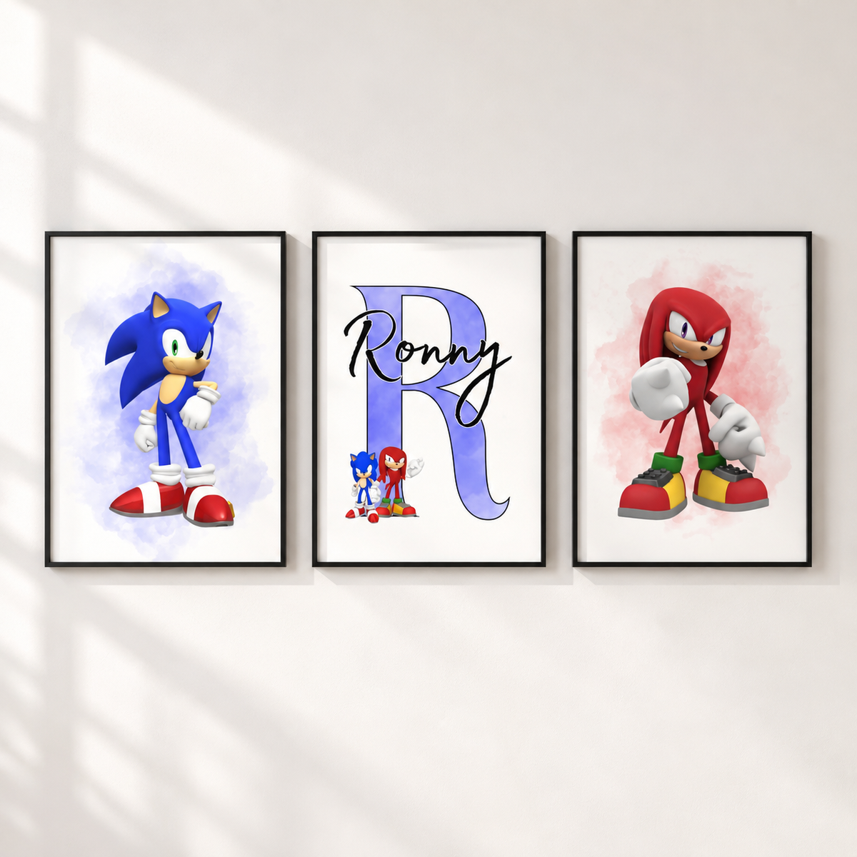 Three framed custom Sonic the Hedgehog wall art prints displayed on a white wall. The left print shows Sonic with a blue watercolor background, the center print features a large personalized letter 'R' with 'Ronny' in script, and the right print shows Sonic Knuckles with a red watercolor background.