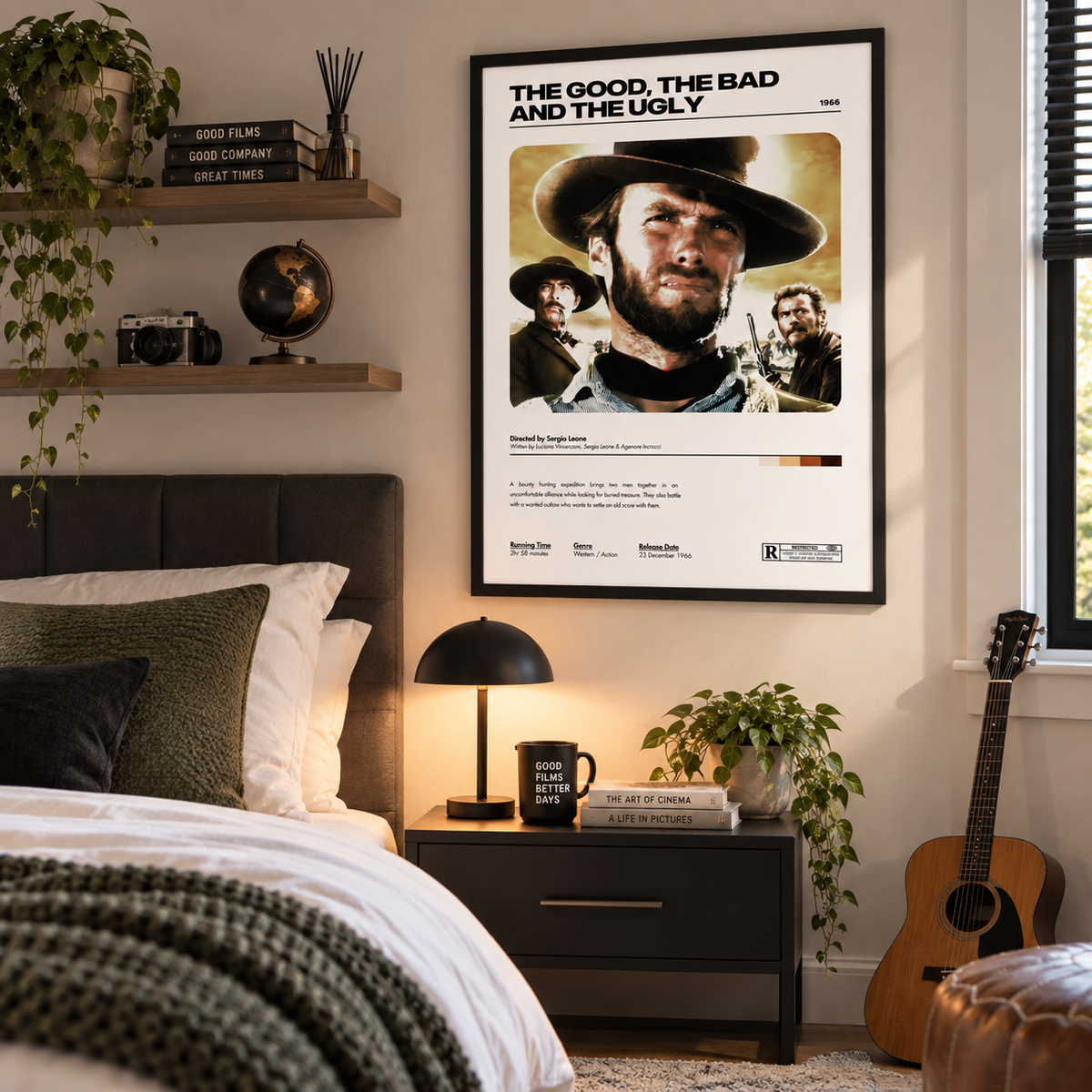 A framed Western movie poster for 'The Good, The Bad and the Ugly' hanging on a bedroom wall above a nightstand, styled with a bed, lamp, plants, and an acoustic guitar.