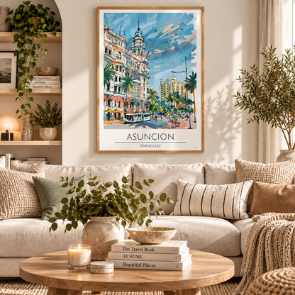 A framed travel poster of Asuncion, Paraguay, hanging on a beige wall above a modern beige sectional sofa in a styled living room. The poster features a colorful watercolor painting of a historic street scene with palm trees and a blue sky, framed in light wood.