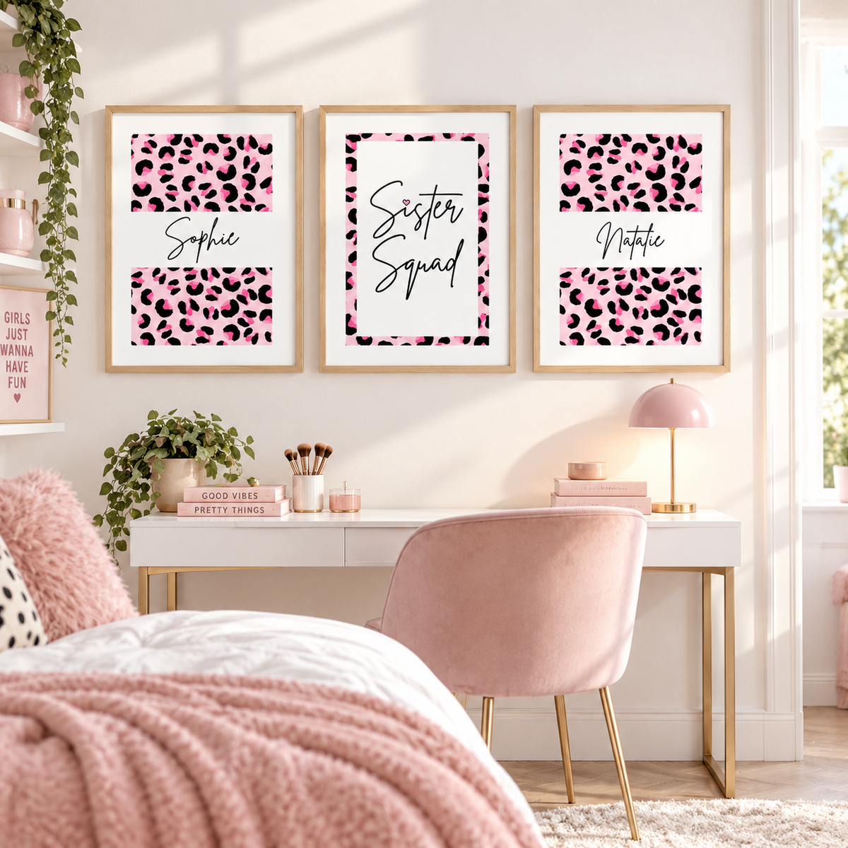 Three framed personalized leopard print wall art prints hang above a white desk in a styled bedroom. The prints feature pink and black leopard patterns with the names Sophie, Sister Squad, and Natalie.