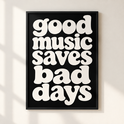 A framed typographic wall art print with the phrase “good music saves bad days” in large white retro letters on a black background, hanging on a light wall with soft shadow overlays.