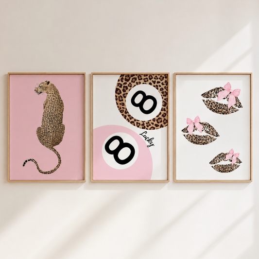 Three framed wall art prints arranged side by side on a light beige wall with soft diagonal shadows. The left print shows a leopard in profile on a pink background.