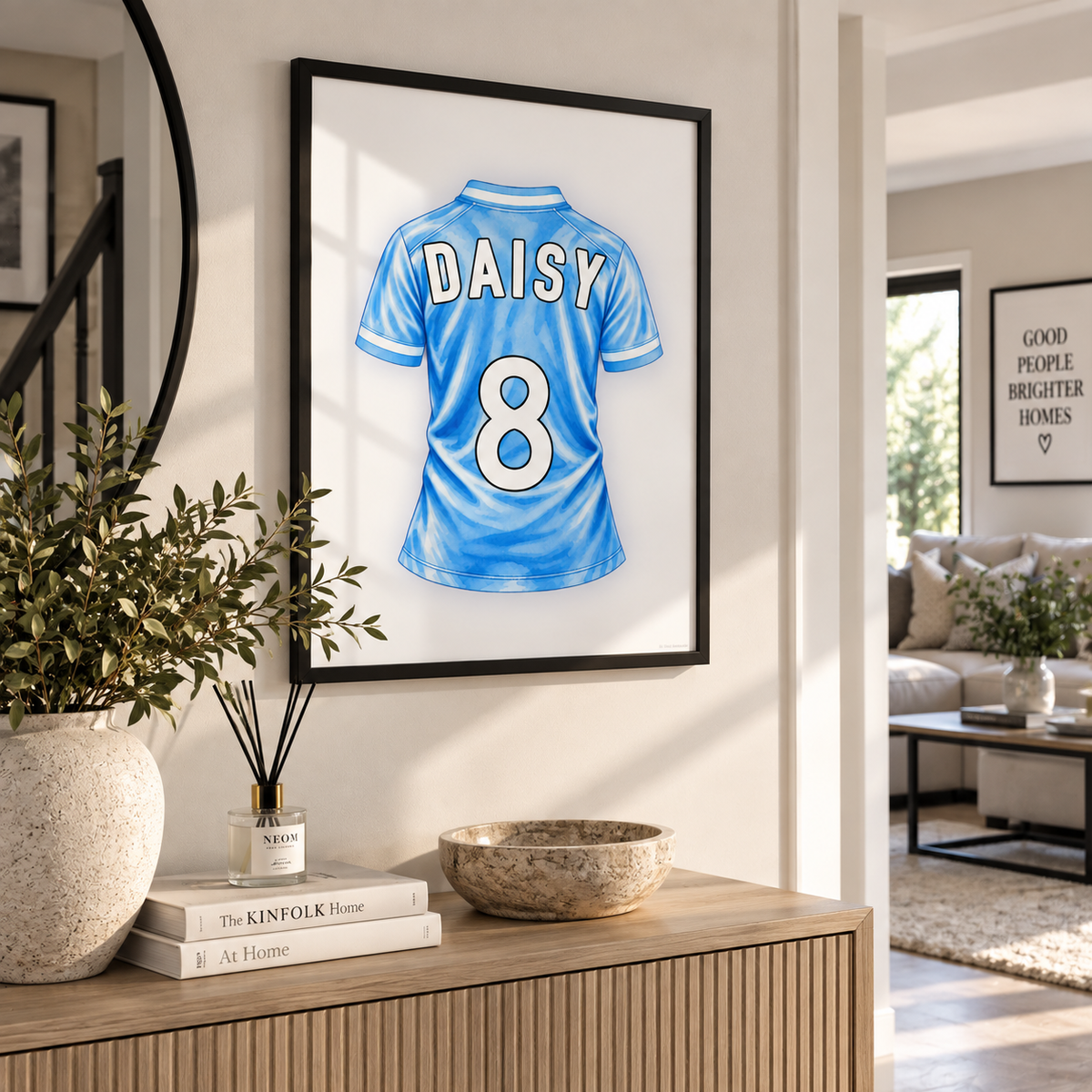 A framed custom jersey print featuring a light blue soccer-style shirt with the name DAISY and number 8 on the back, displayed on a wall in a modern living room setting above a wooden console table.