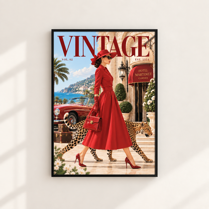 A framed vintage-style art print featuring a woman in a red dress walking with a leopard in front of a Mediterranean building, styled like a retro magazine cover. The print is displayed on a light beige wall with soft window shadows.