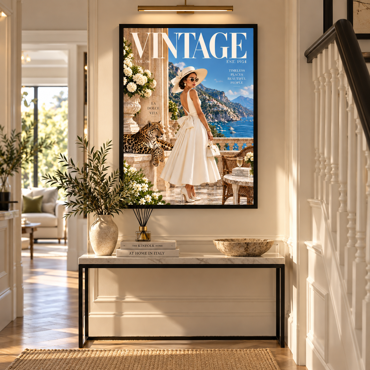 A framed vintage-style magazine cover art print hangs on a white hallway wall above a console table. The print features a woman in a white dress by a blue seaside or mountain backdrop, with large 'VINTAGE' text at the top.