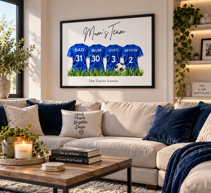 A framed custom family print featuring four blue football jerseys with player numbers, hung on a beige wall above a sofa in a styled living room.