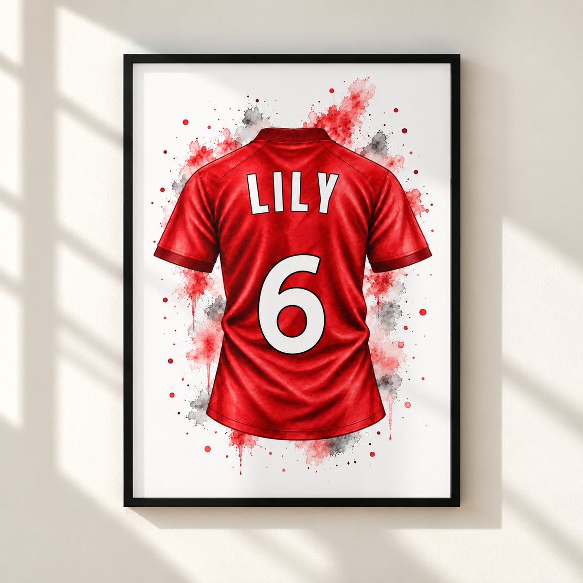 Framed wall art featuring a red soccer jersey back design with the name LILY and number 6 in white, shown hanging on a light wall with soft window shadows.