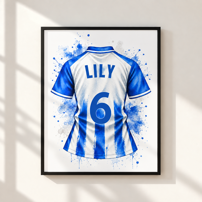 Framed wall art featuring a blue and white striped soccer jersey with the name LILY and number 6 on the back, displayed on a light beige wall with soft window-shadow lighting.