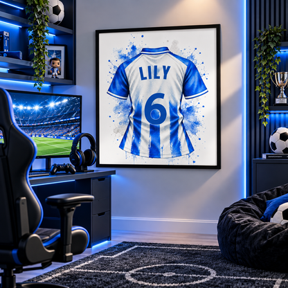 A framed wall art print featuring the back of a blue and white striped soccer jersey with 'LILY 6' in blue, displayed in a modern gaming room with a desk, chair, monitor, and beanbag.