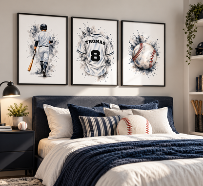 Three framed baseball-themed wall art prints hang above a bed in a styled bedroom. The prints show a watercolor-style baseball player, a white baseball jersey with the number 8 and the name THOMAS, and a baseball with red stitching.
