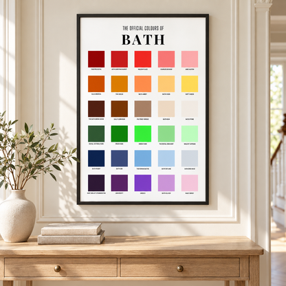 A framed wall poster reading 'THE OFFICIAL COLOURS OF BATH' hangs on a cream wall above a wooden console table. The print contains a grid of many color swatches in reds, oranges, yellows, browns, neutrals, greens, blues, purples, and pinks.