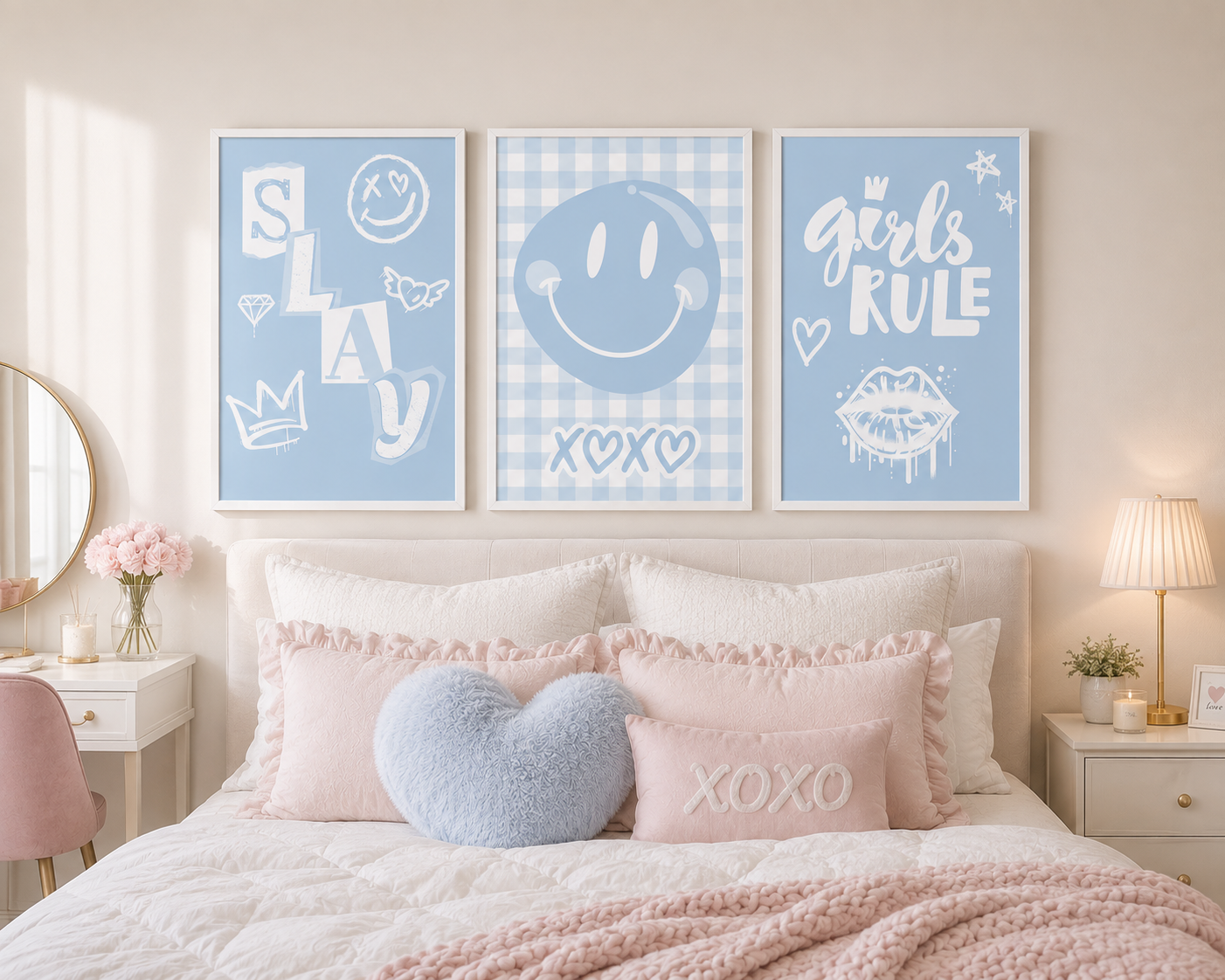 Three framed pastel blue decorative wall art prints hang above a bed in a softly styled bedroom. The prints read 'SLAY', 'girls RULE', and 'XOXO' with smiley faces, stars, and gingham patterns.