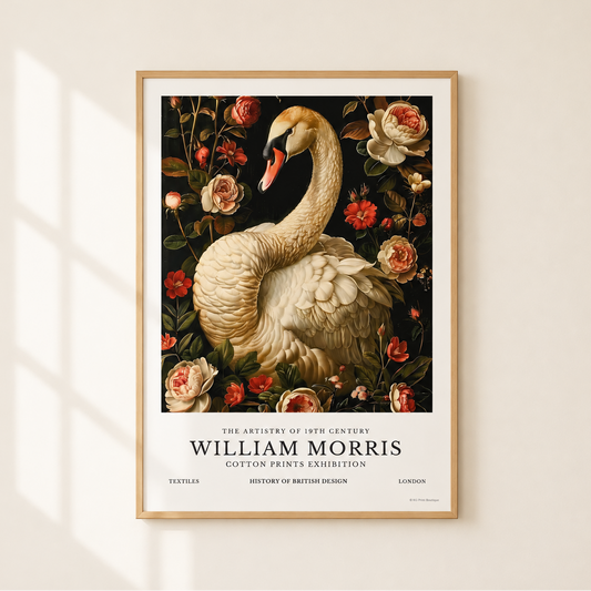 A framed art print featuring a vintage illustration of a white swan surrounded by red and pink roses on a dark background, with the text 'William Morris' and 'Cotton Print & Exhibition' at the bottom. The print is displayed on a light beige wall with soft window shadow lighting.