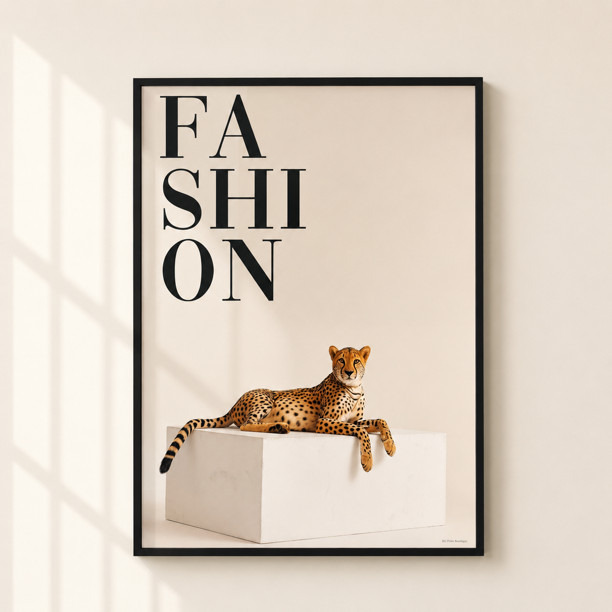A framed fashion poster featuring the word 'FASHION' in large black letters above an illustration of a cheetah resting on a white pedestal, displayed on a light beige wall with soft window shadows.