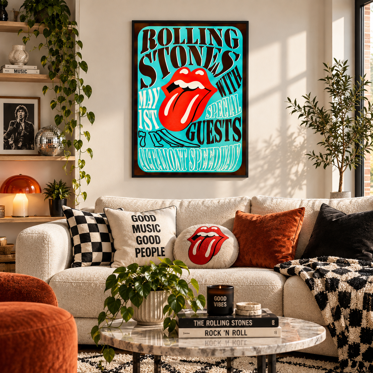 A framed Rolling Stones poster featuring the classic red lips and tongue logo on a turquoise background, hanging on a light beige wall above a cream sofa with decorative pillows in a styled living room.