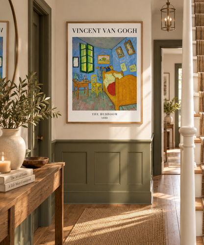 A framed art print of Vincent van Gogh's 'The Bedroom' hanging on a wall in a beautifully styled hallway with green wainscoting, a wooden console table, and a woven rug.