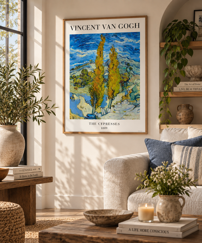 A framed Vincent van Gogh 'The Cypress' art print hangs on a beige wall in a styled living room with a sofa, plants, and wooden furniture.