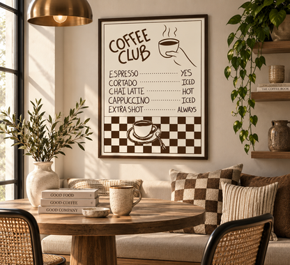 A framed wall art print with a retro coffee menu design hangs above a sofa in a styled living room. The print features brown text and graphics on a cream background, including the words 'COFFEE CLUB' and coffee drink options with yes/no answers.