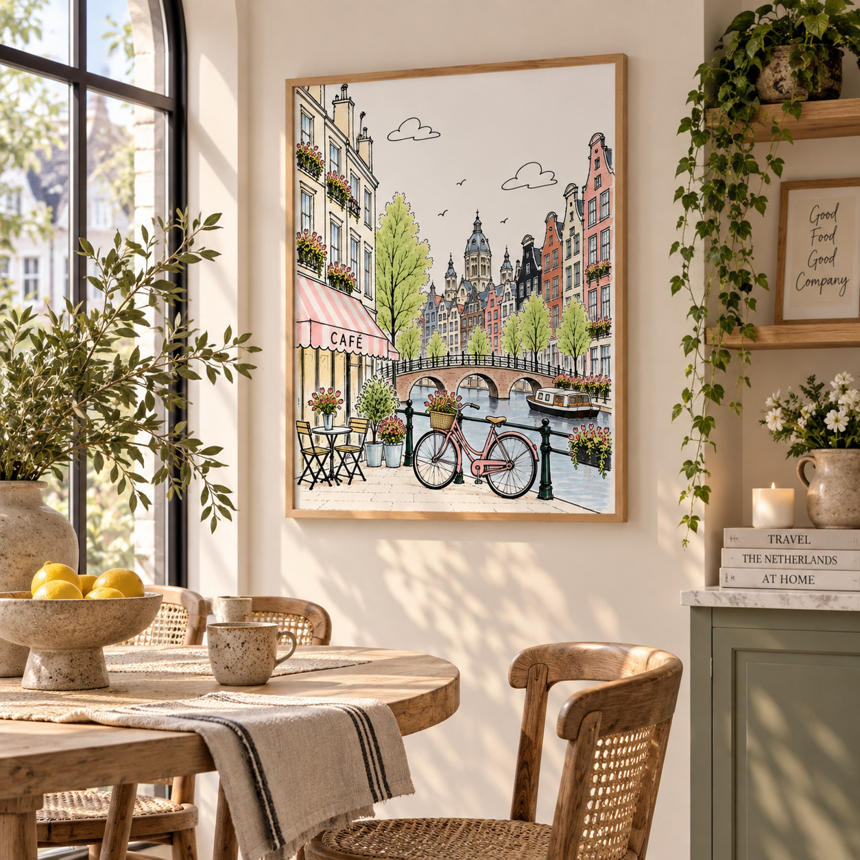 A framed art print depicting a charming Amsterdam canal scene with a bicycle, hanging on a wall in a beautifully styled dining room with wooden furniture and green plants.