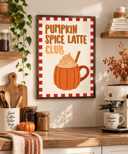 A framed wall art print reading “Pumpkin Spice Latte Club” hangs on a warm beige wall above a wooden counter. The print shows an orange pumpkin mug filled with whipped cream and a cinnamon stick, surrounded by a red-and-white check border.