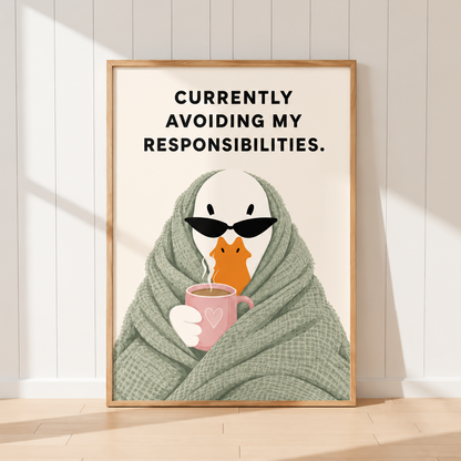 A framed art print leaning against a white paneled wall on a light wood floor. The print features a cartoon penguin wrapped in a green blanket and wearing black sunglasses, holding a pink mug.