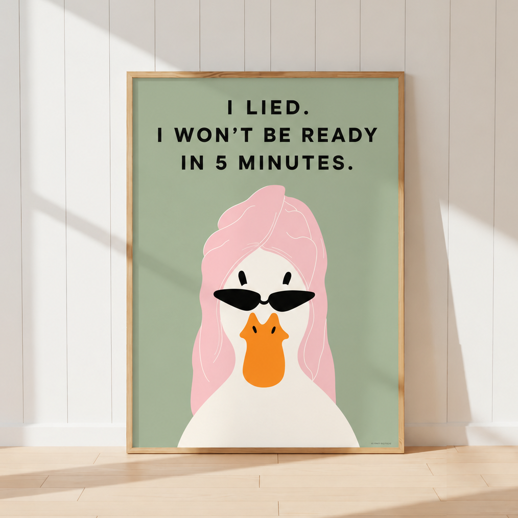 A framed art print featuring a minimalist illustration of a white duck with pink hair and black sunglasses, with the text 'I LIED. I WON'T BE READY IN 5 MINUTES.
