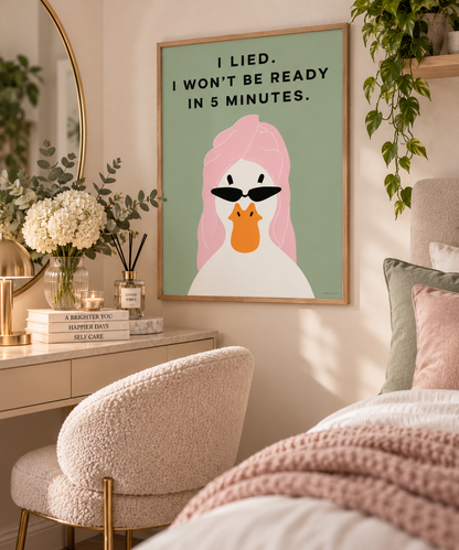 A framed art print featuring a stylized white duck with pink hair and black sunglasses, with the text 'I LIED. I WON'T BE READY IN 5 MINUTES.