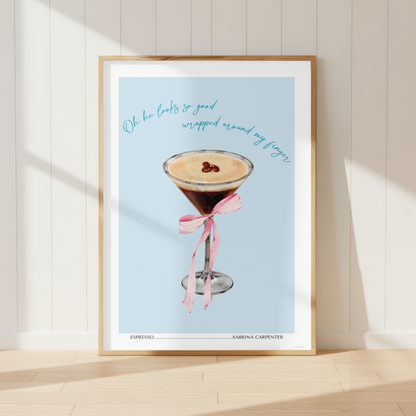 Sabrina Carpenter inspired Espresso wall art print featuring an espresso martini with a pink ribbon bow, displayed in a stylish pastel kitchen.