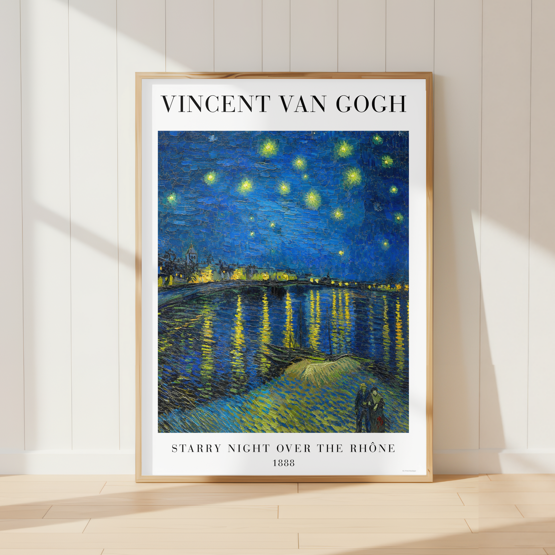 A framed art print of Vincent van Gogh's 'Starry Night Over the Rhine' (1888) leaning against a white paneled wall on a light wood floor, with soft window shadows cast across the scene.