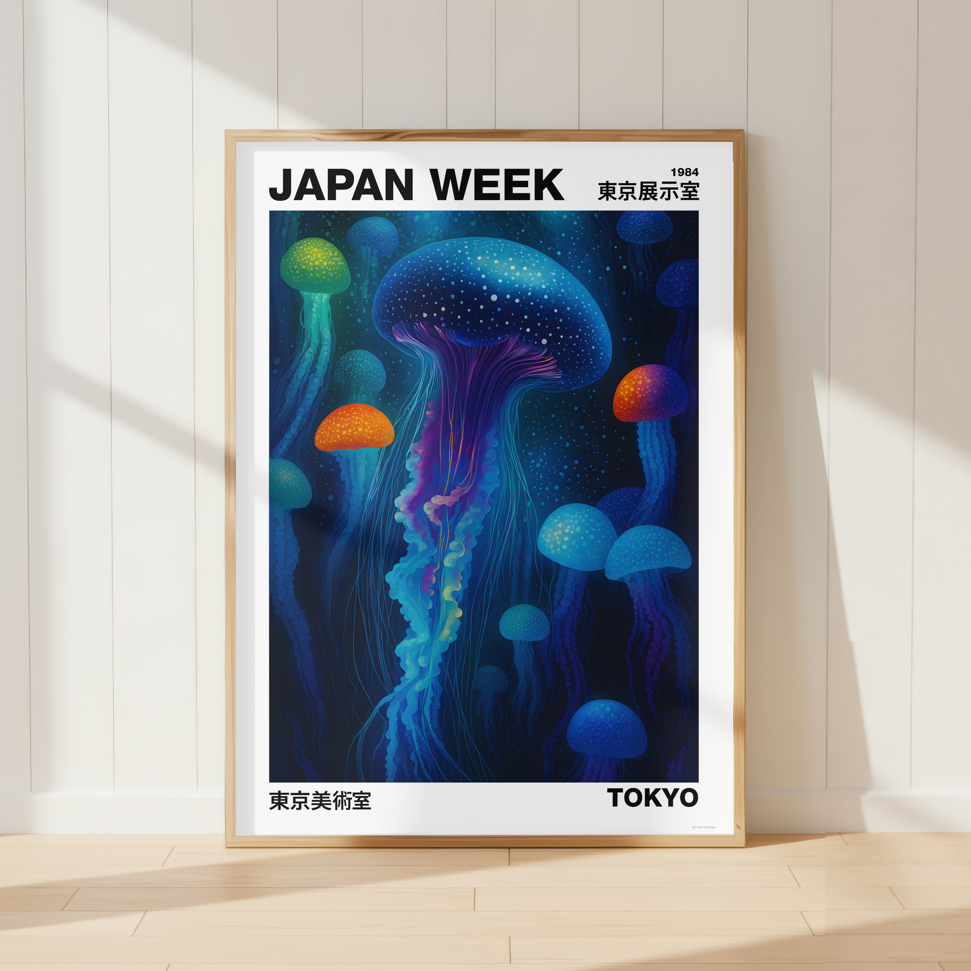 A framed poster leaning against a white paneled wall on a light wood floor. The poster features a colorful illustration of glowing jellyfish in deep blue, purple, green, and orange tones, with the text 'JAPAN WEEK' at the top and 'TOKYO' at the bottom.
