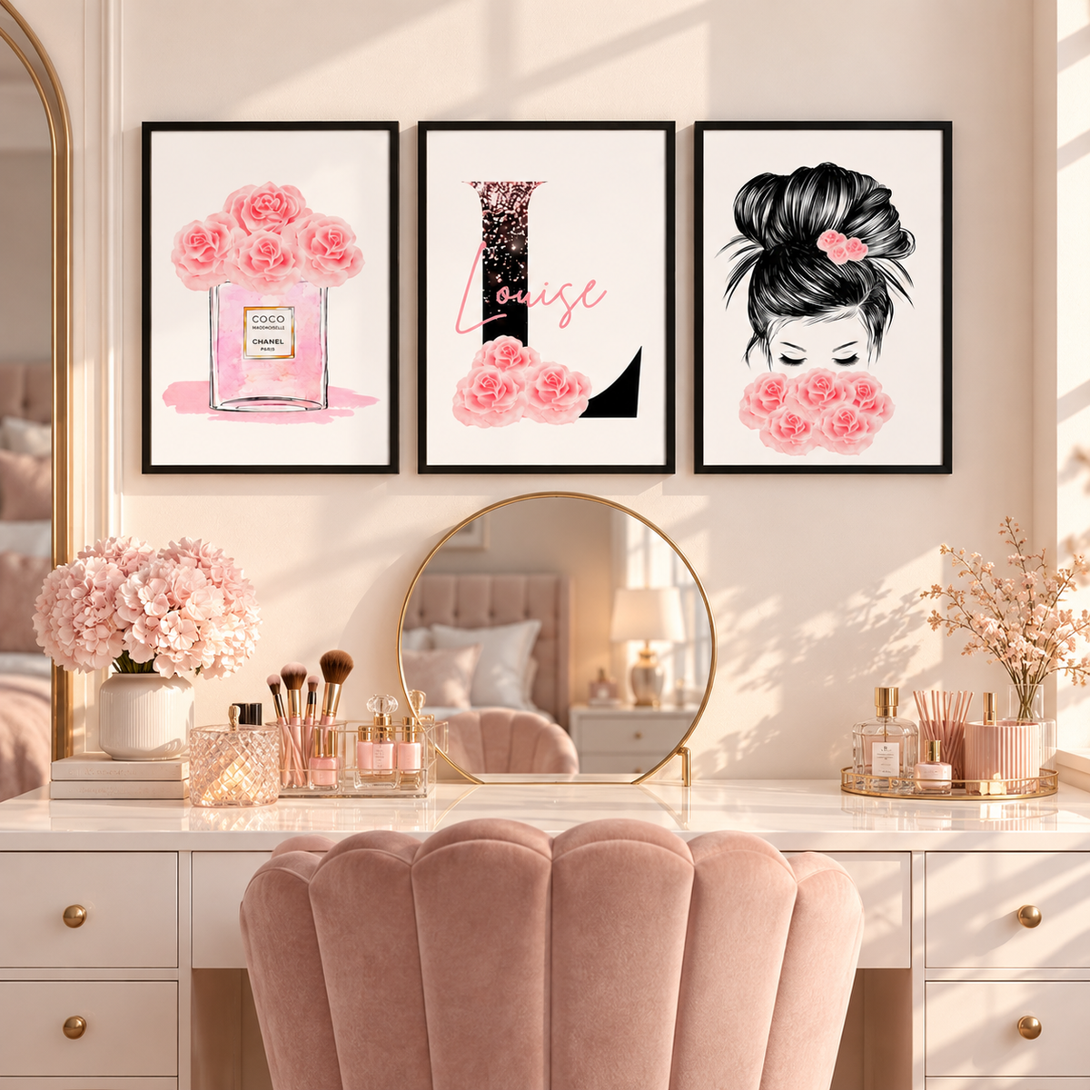 Three framed art prints featuring pink roses, a perfume bottle, and a black-and-white illustration with the word 'Lise' are displayed above a vanity desk in a beautifully styled room with a pink velvet chair and gold-framed mirrors.